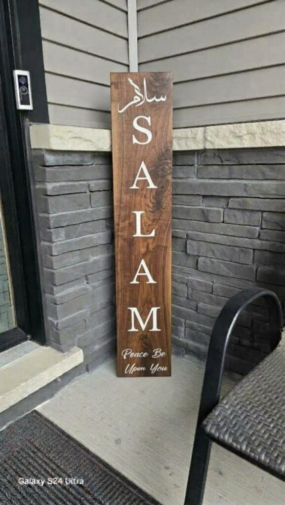 Custom walnut wood Salam porch sign leaning against front entrance stone wall