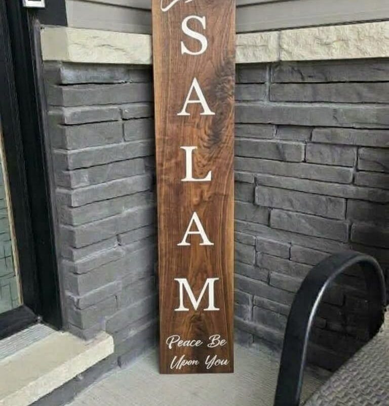 Custom walnut wood Salam porch sign leaning against front entrance stone wall